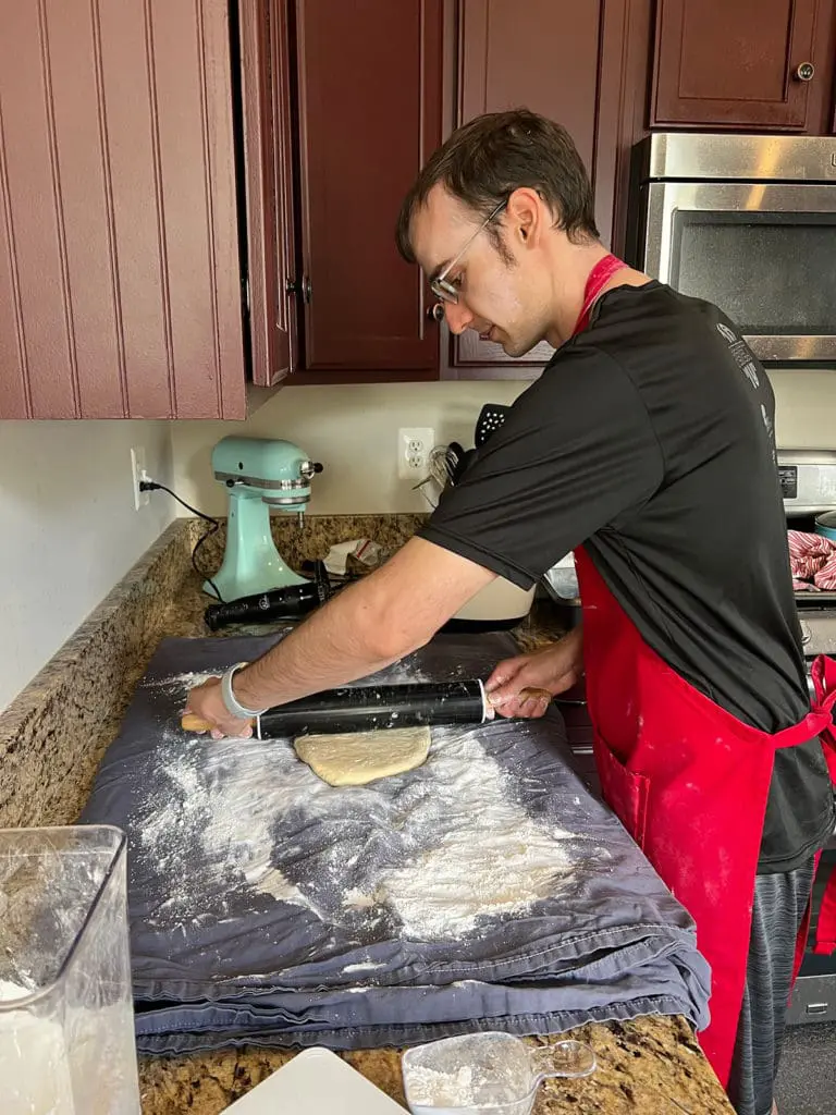 Xak rolling out povitica dough on the bedsheet