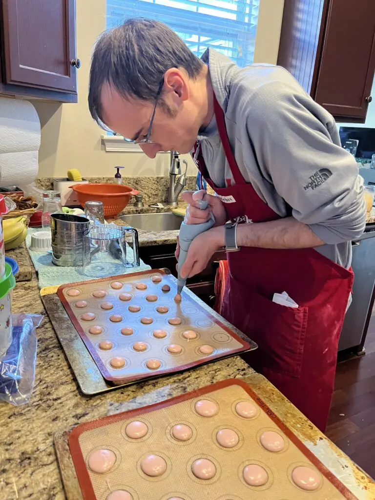 Piping macaron batter onto cookie sheet
