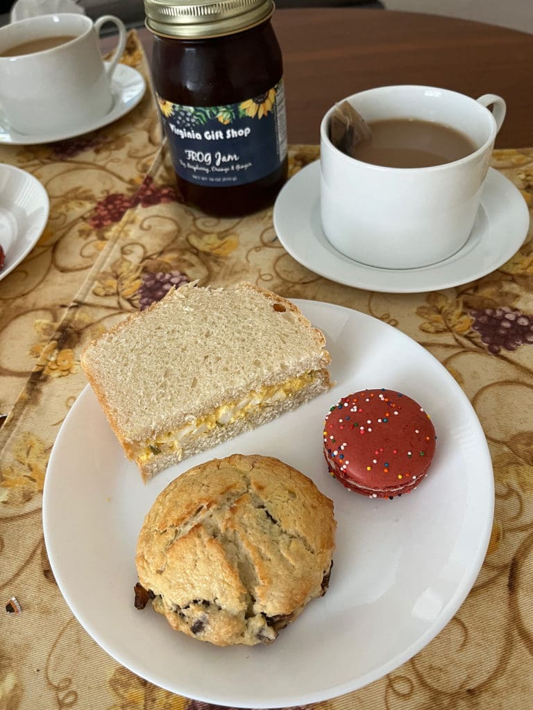 A plate with fig scone, macaron, and egg sandwich
