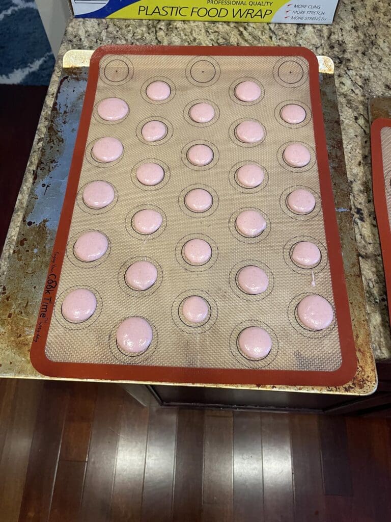 Macarons piped on cookie sheet